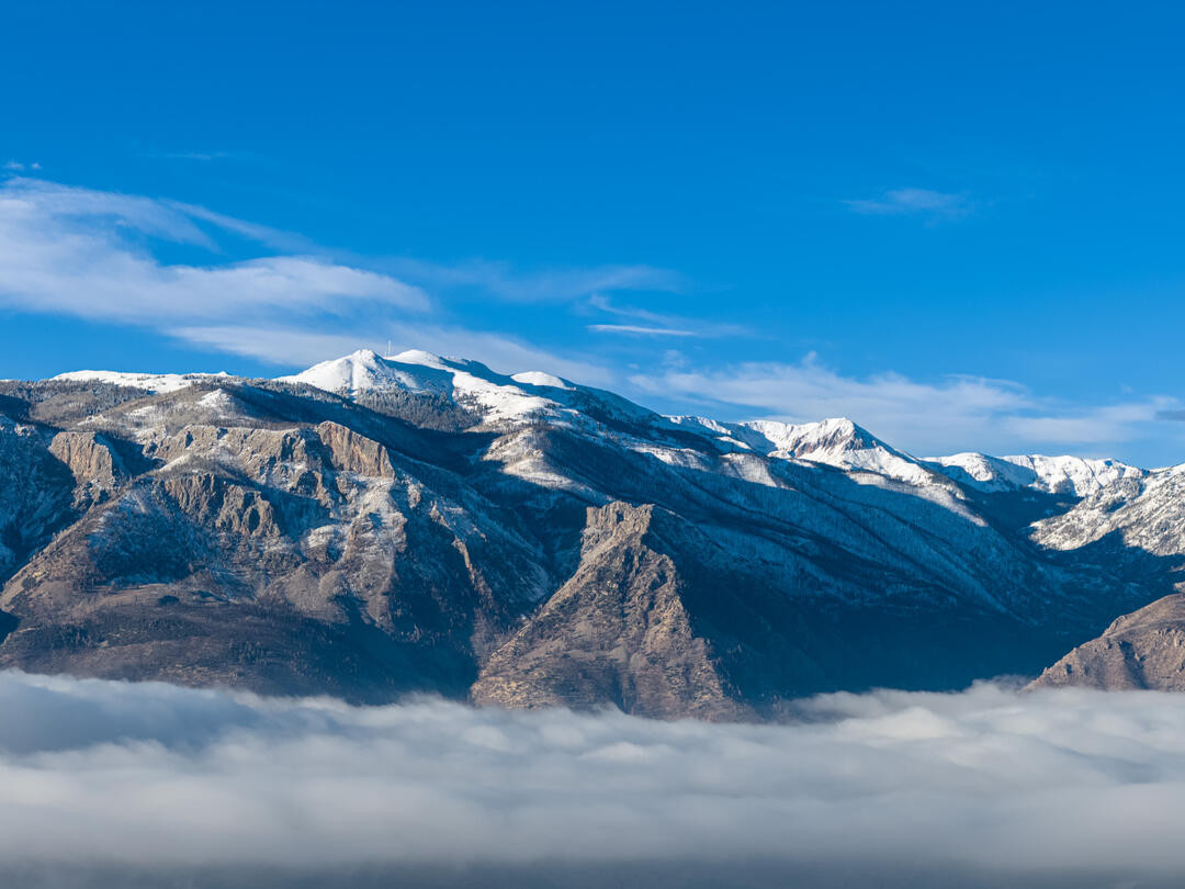 A mountain with snow above the clouds