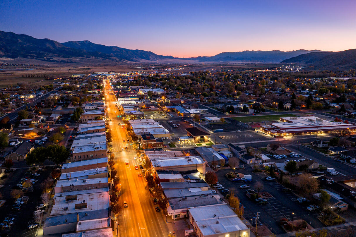 An aerial photo of a cityscape at dusk with mountains