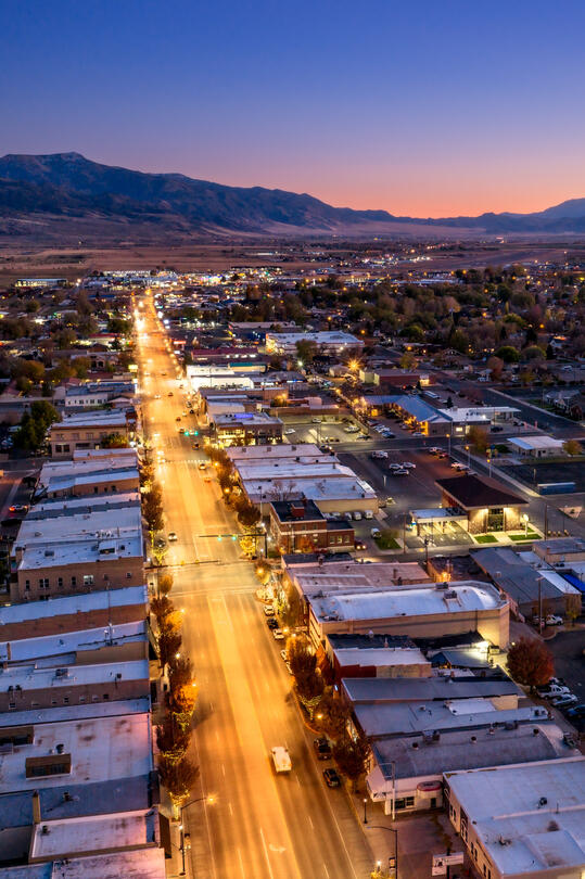 An aerial photo of a cityscape at dusk with mountains